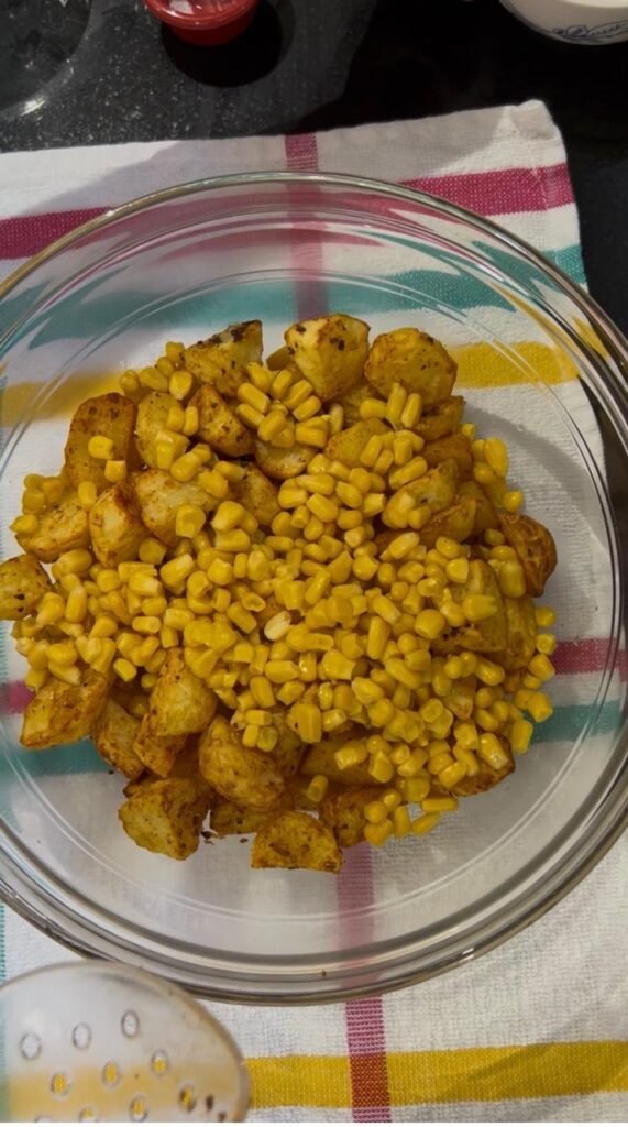 Sweet corn added to air fried potatoes in a mixing bowl