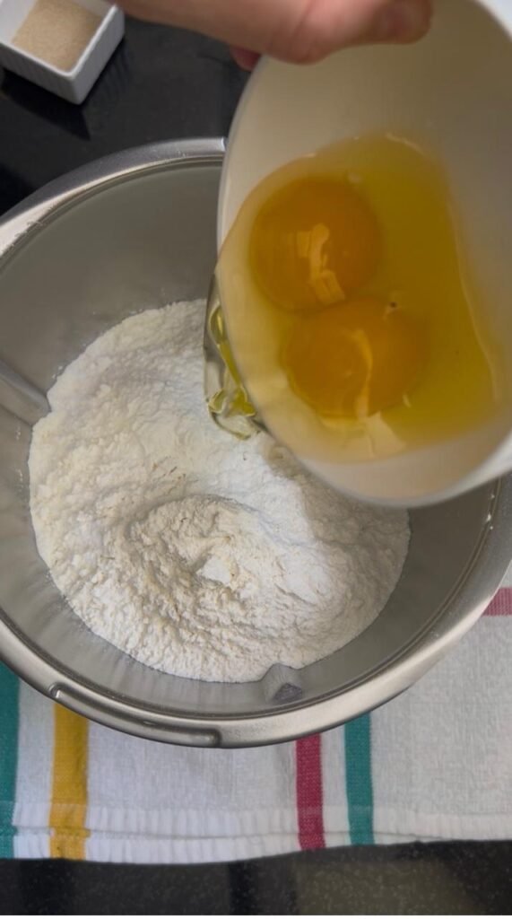 Two eggs poured into flour for banana roll dough