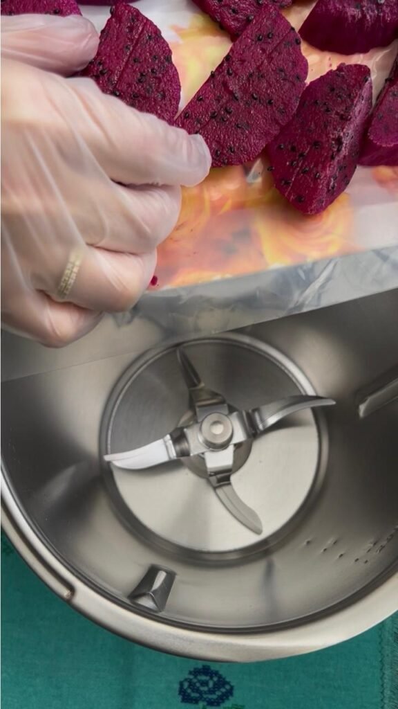 Adding frozen dragon fruit pieces into a blender