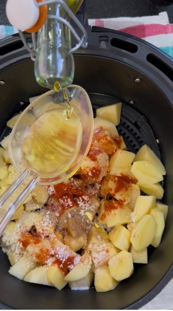 Olive oil drizzled over seasoned potato cubes before air frying