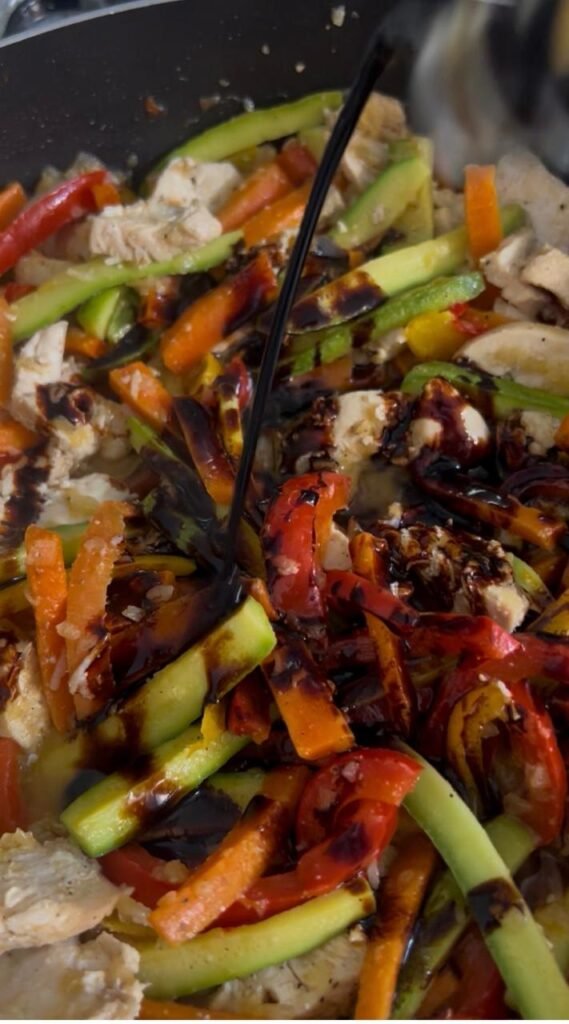Pouring soy sauce over the chicken and vegetables