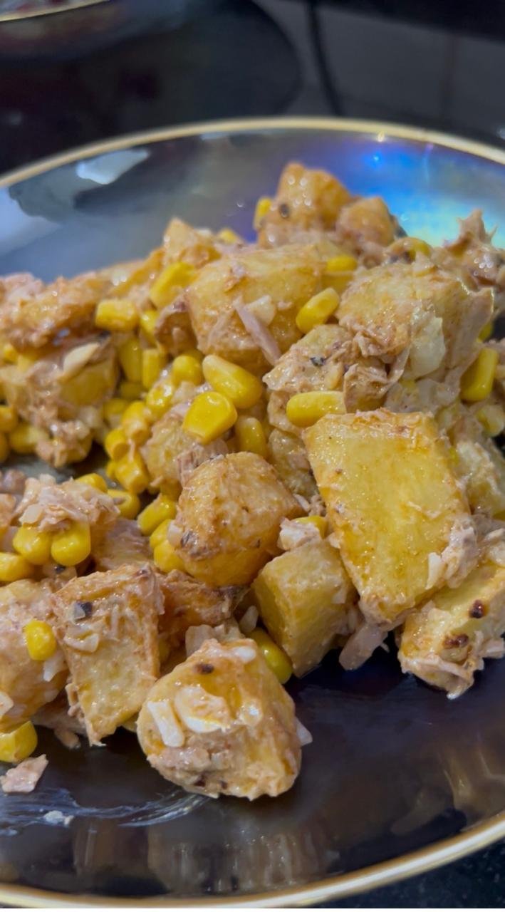 Air fryer potato salad served in a dark bowl with a spoon