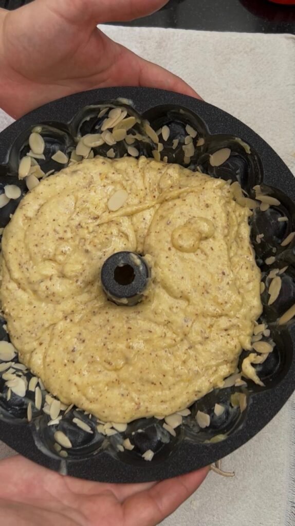 Almond cake batter poured over sliced almonds in Bundt pan