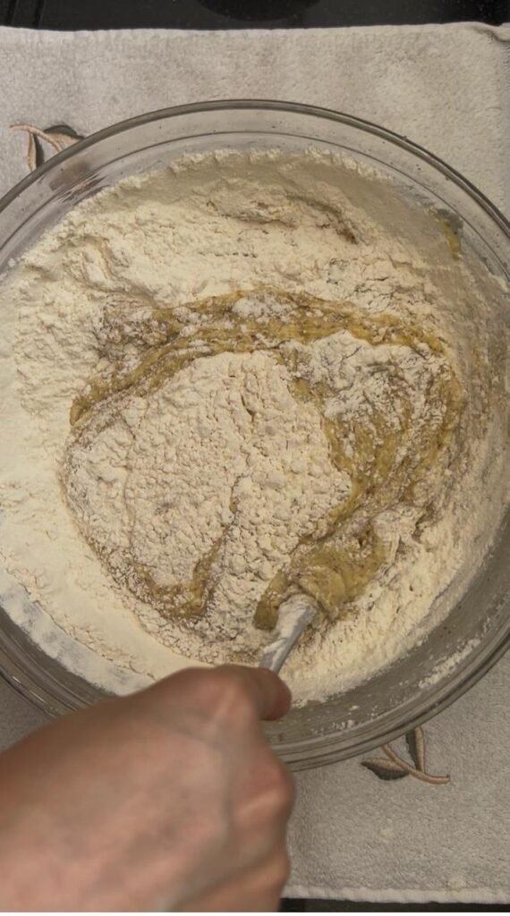 Gently folding sifted flour into the batter
