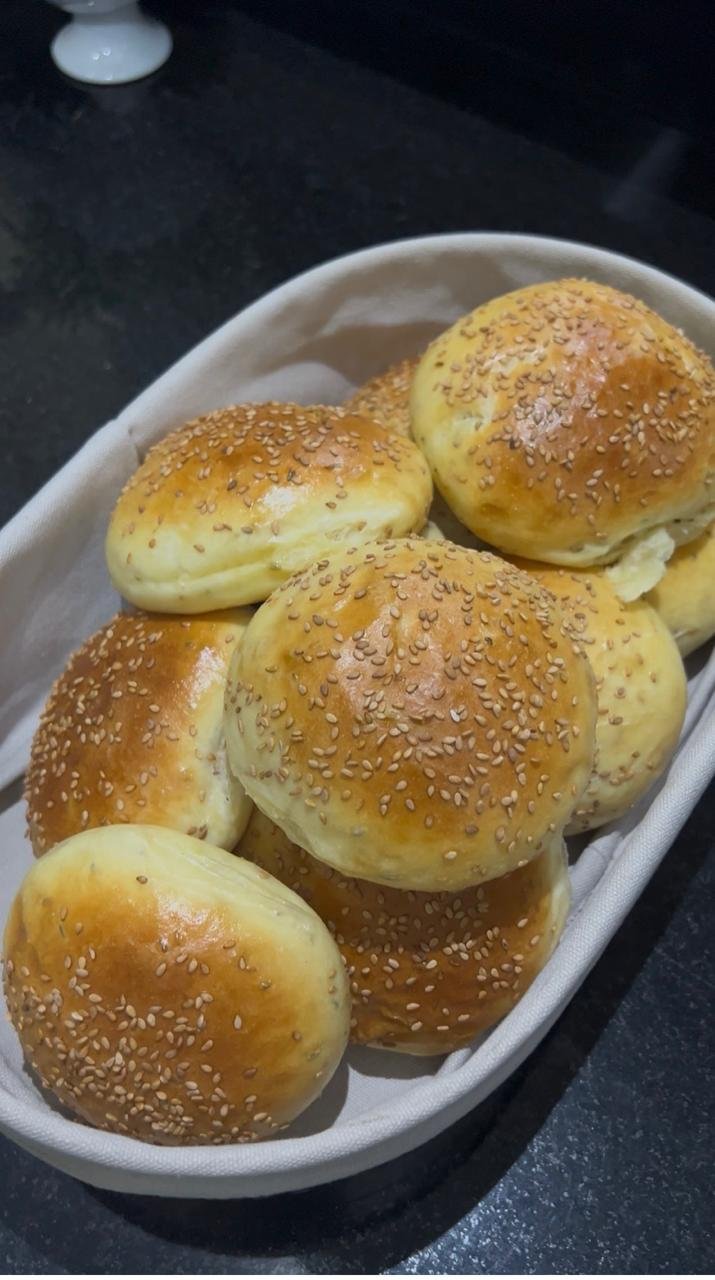Golden banana dinner rolls topped with sesame seeds in a bread basket