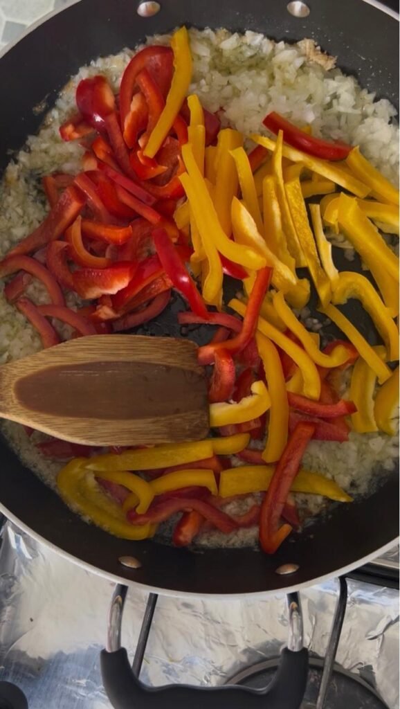 Red and yellow bell peppers added to the pan