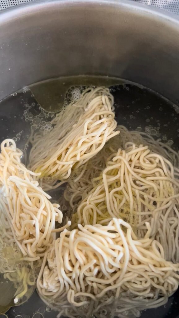 Noodles boiling in water before draining