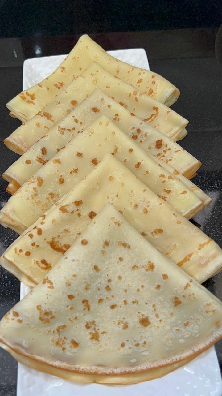 Stack of folded buttermilk crepes on a white plate
