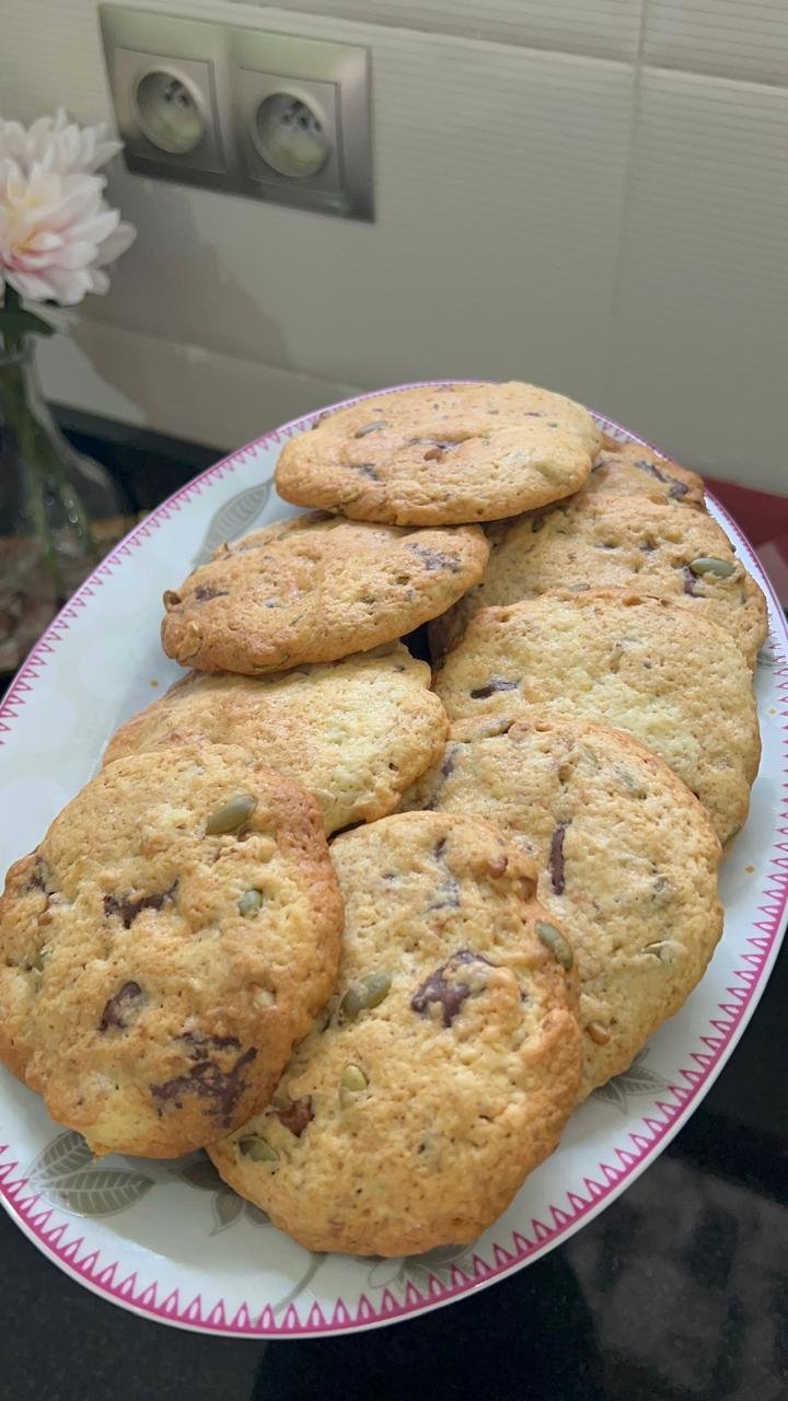 Chocolate walnut cookies with pumpkin seeds arranged on a white serving plate