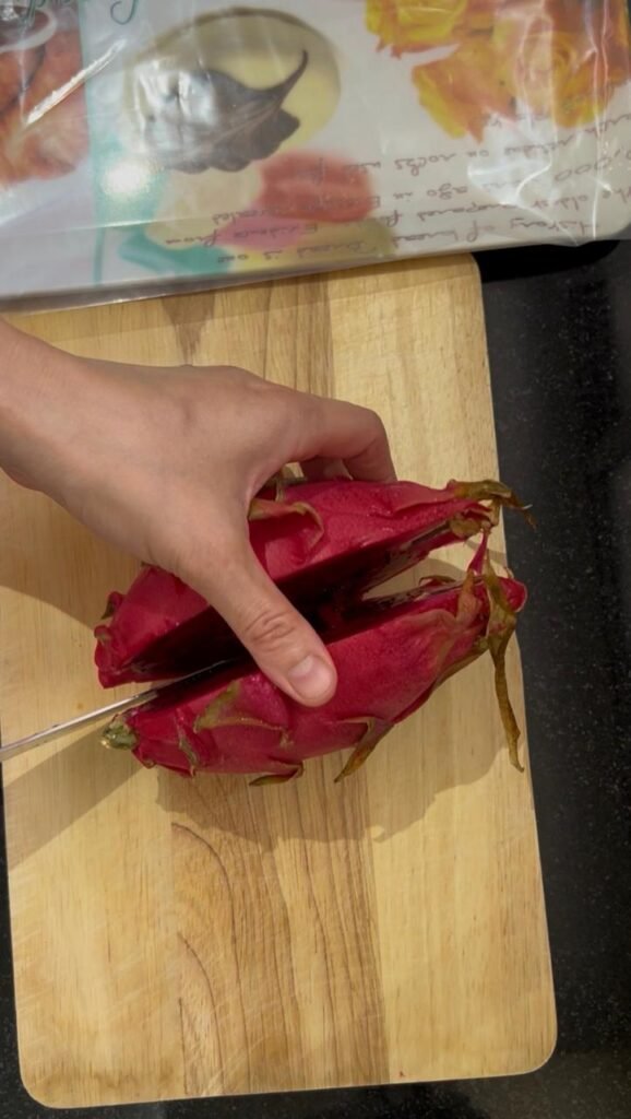 Whole red dragon fruit cut in half showing pink flesh