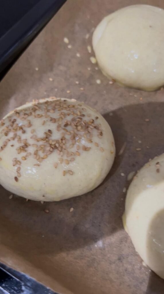 Risen banana roll brushed with egg wash and topped with sesame seeds