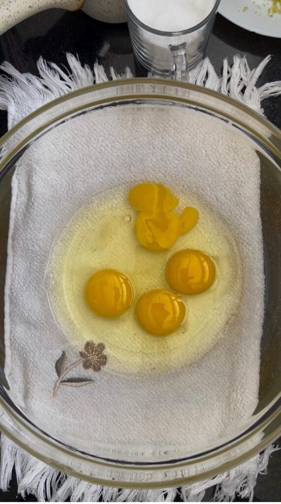 Four eggs cracked into a glass bowl to start the batter