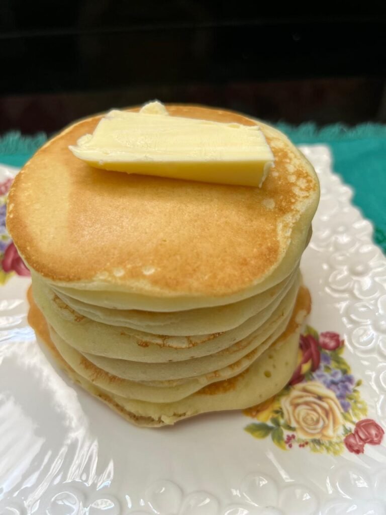 Stack of fluffy buttermilk pancakes topped with a pat of butter