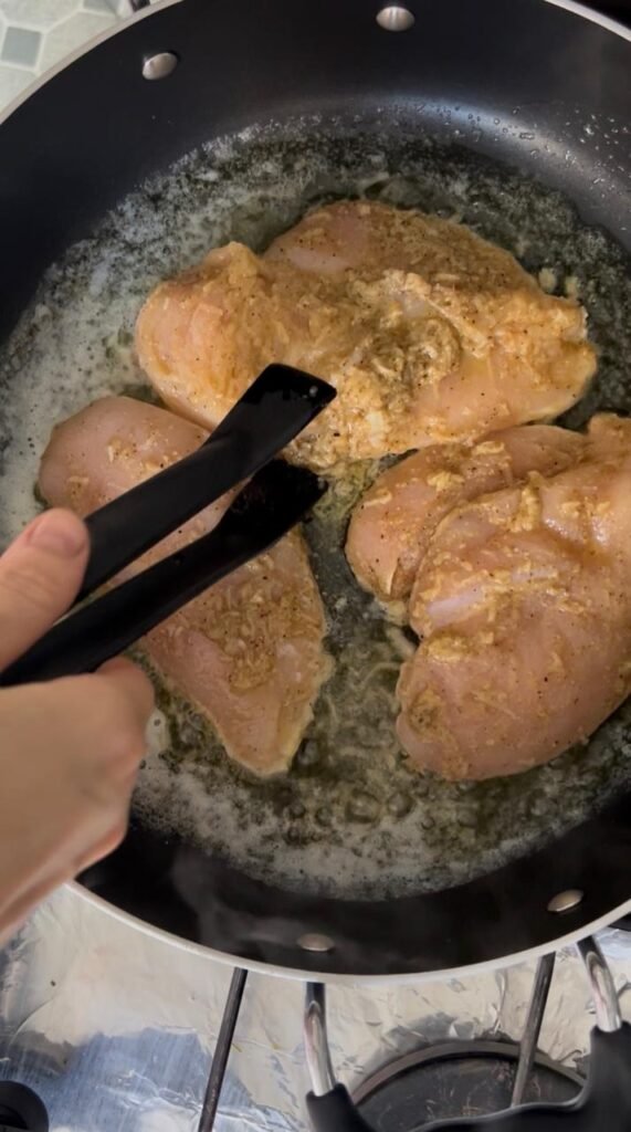 Marinated chicken breast starting to sear in butter and oil