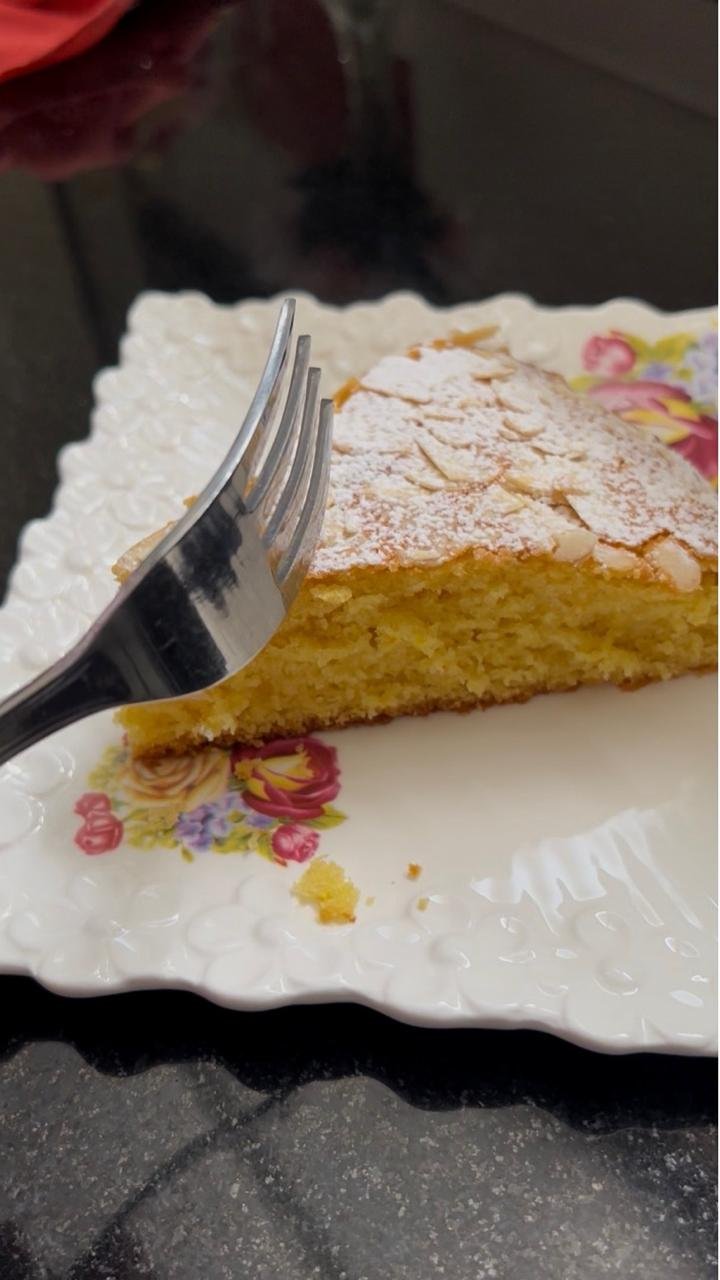 Slice of orange almond cake on a plate with a tender golden crumb