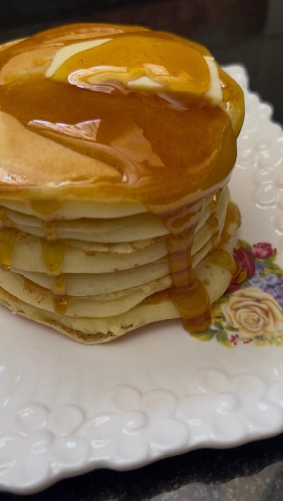Fluffy buttermilk pancakes with butter and syrup running down the stack