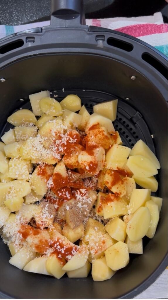 Cubed potatoes with paprika, dried onion and coriander in an air fryer basket