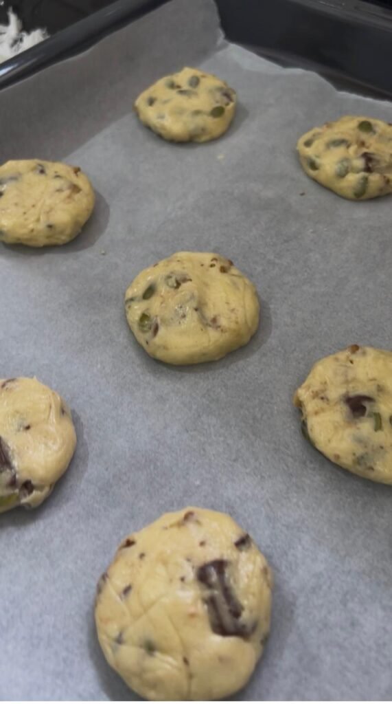 Flattened balls of cookie dough spaced on a parchment lined baking sheet