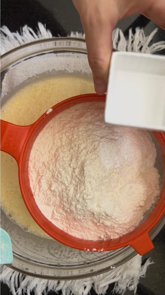 Flour and baking powder sifted over the wet ingredients