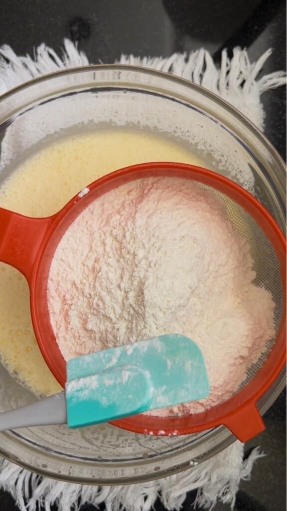 Sifting the dry ingredients in stages for a smooth batter
