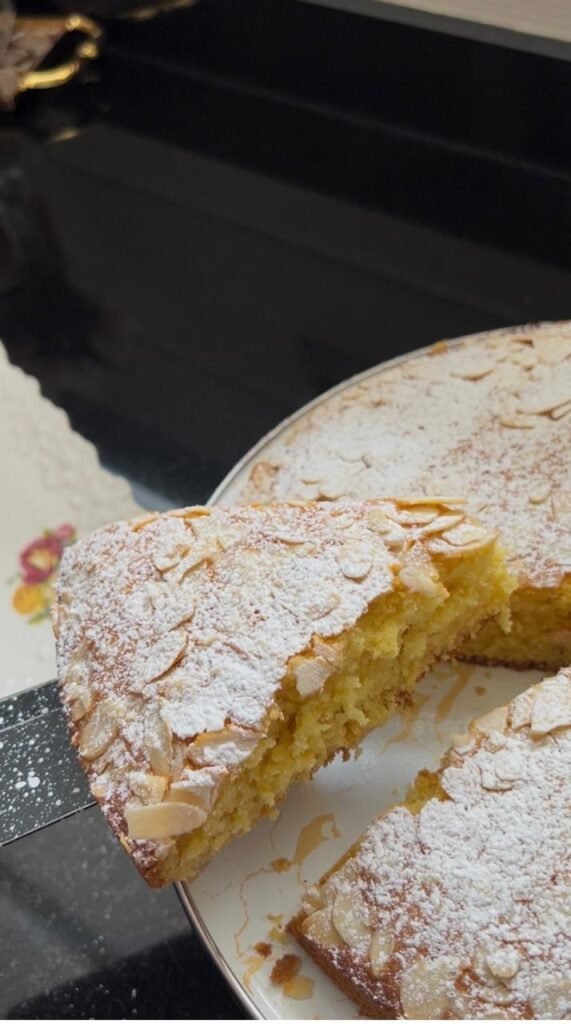 A slice of moist orange almond cake lifted from the whole cake
