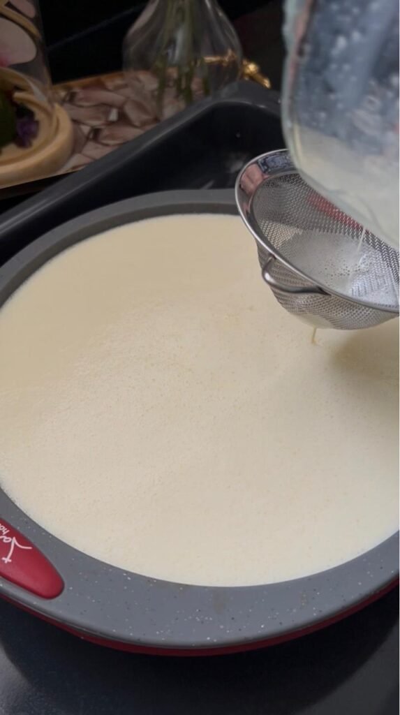 Straining the flan mixture through a sieve for a silky texture
