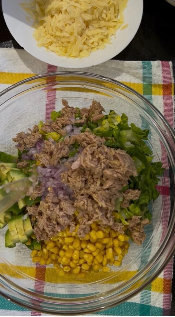 Drained canned tuna flaked over vegetables for a tuna wrap filling