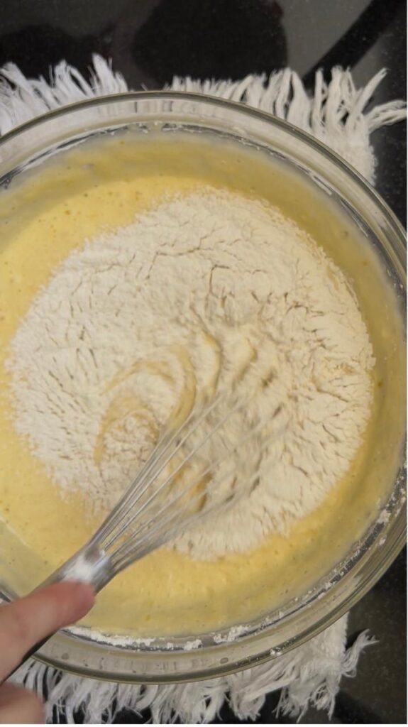 Whisking the flour gently into the batter to avoid overworking it