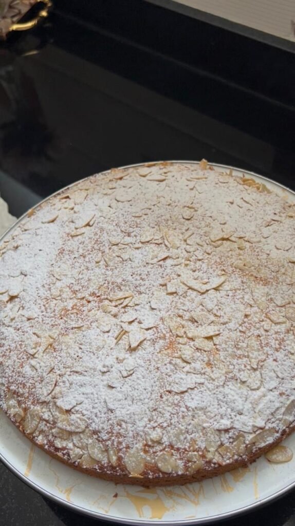 Whole orange almond cake topped with sliced almonds and powdered sugar