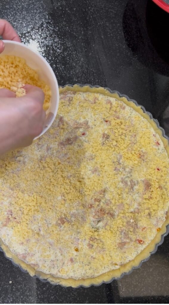 Grated cheese sprinkled over an unbaked tuna and pepper quiche