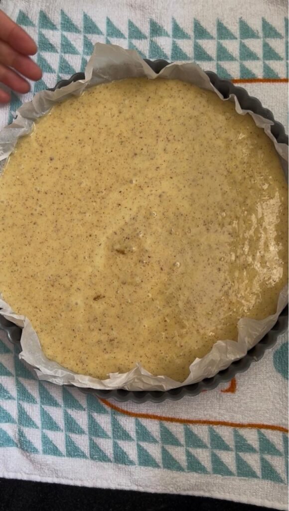 Almond cake batter poured into a parchment-lined pan