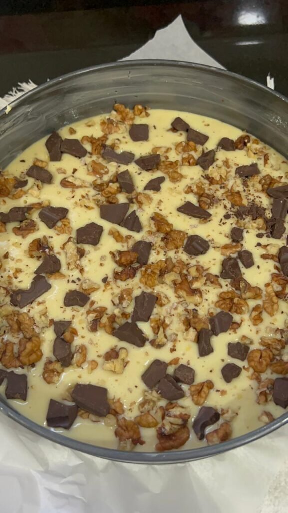 Banana cake batter poured into pan with walnuts and dark chocolate scattered on top