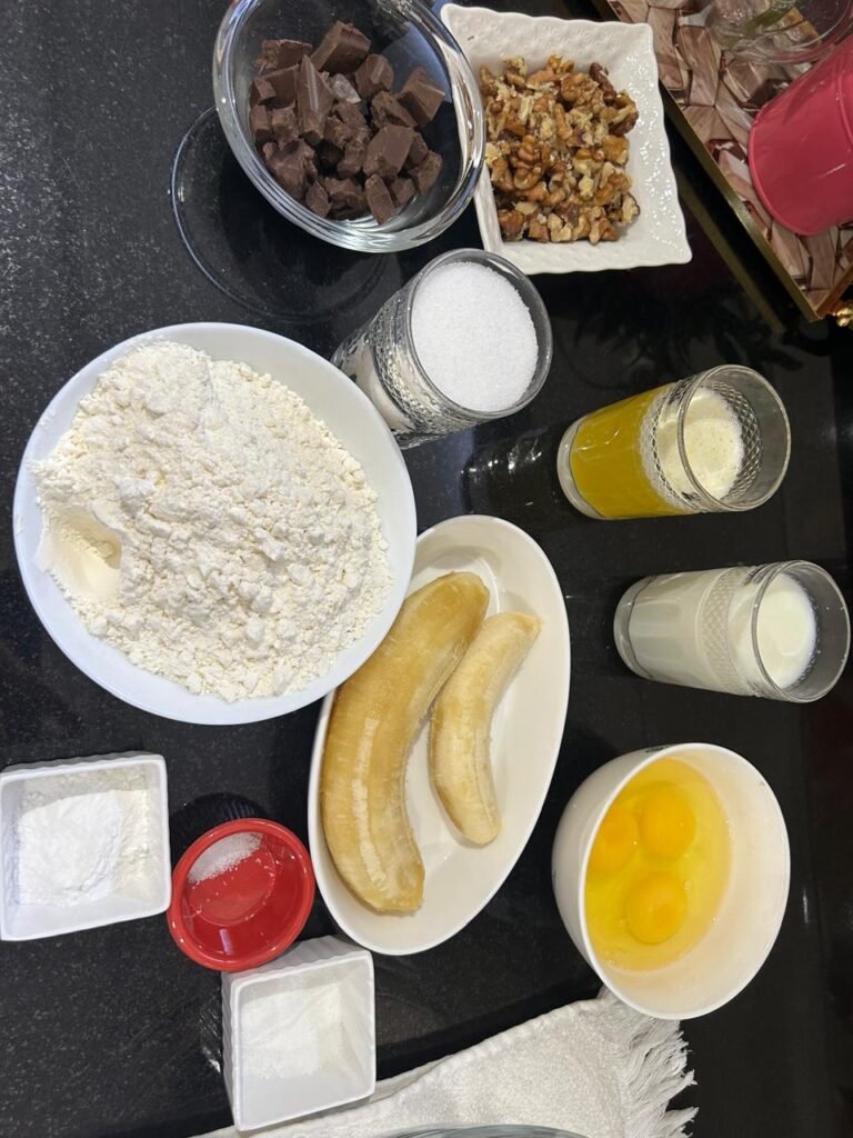 All ingredients for easy banana chocolate cake: flour, vanilla sugar, butter, bananas, walnuts, chocolate