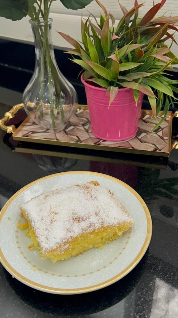 Easy orange basbousa cake slice with powdered sugar and shredded coconut topping