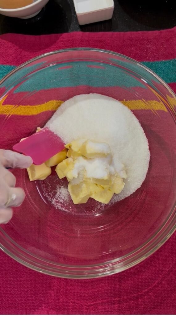 Butter and sugar being creamed in a glass bowl