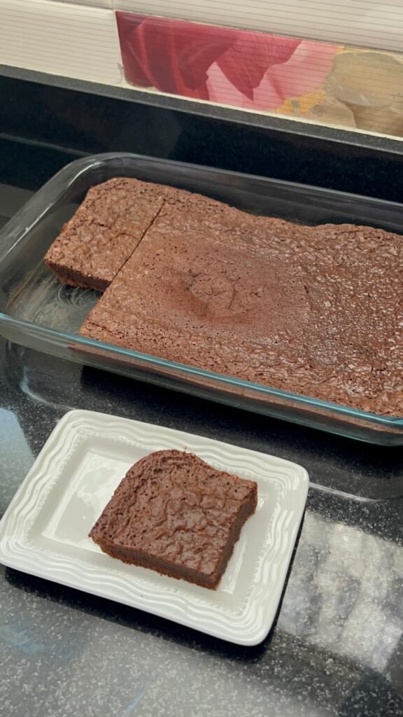 A pan of fudgy brownies with one square on a plate
