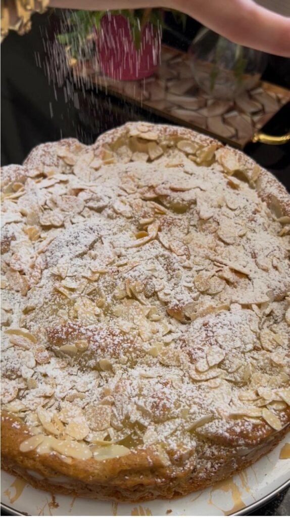 Dusting powdered sugar over a finished lemon almond cake