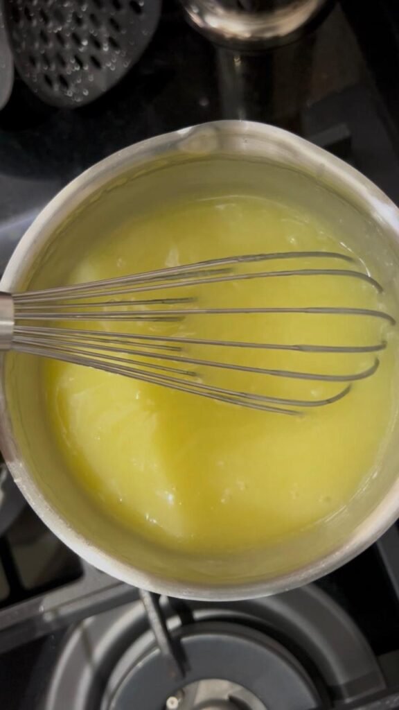 Homemade lemon curd thickening in a saucepan