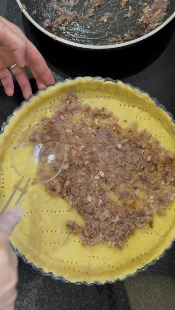 Sauteed onion spread over a pricked quiche crust base