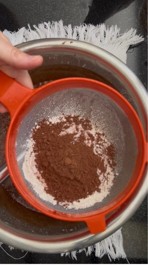 Sifting cocoa and flour into the chocolate brownie batter
