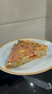 Slice of tuna and pepper quiche showing tuna, roasted peppers and custard filling