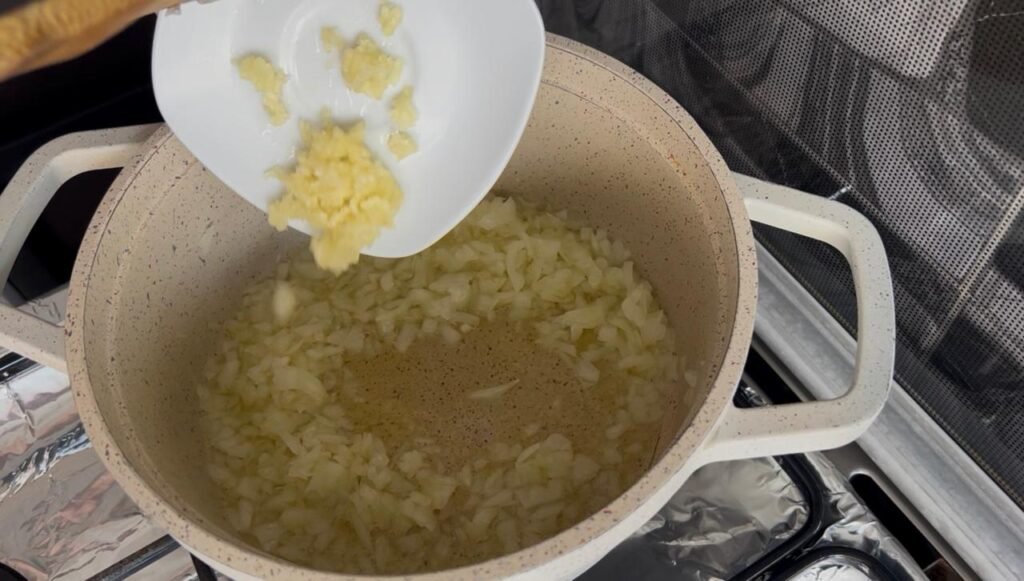 Minced garlic added to softened onions, cooking until fragrant for easy white bean stew