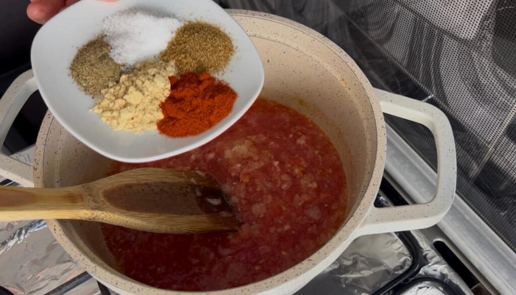 White bowl displaying ground coriander, ground ginger, paprika, salt, and ginger spice blend for easy white bean stew with tomato sauce in background