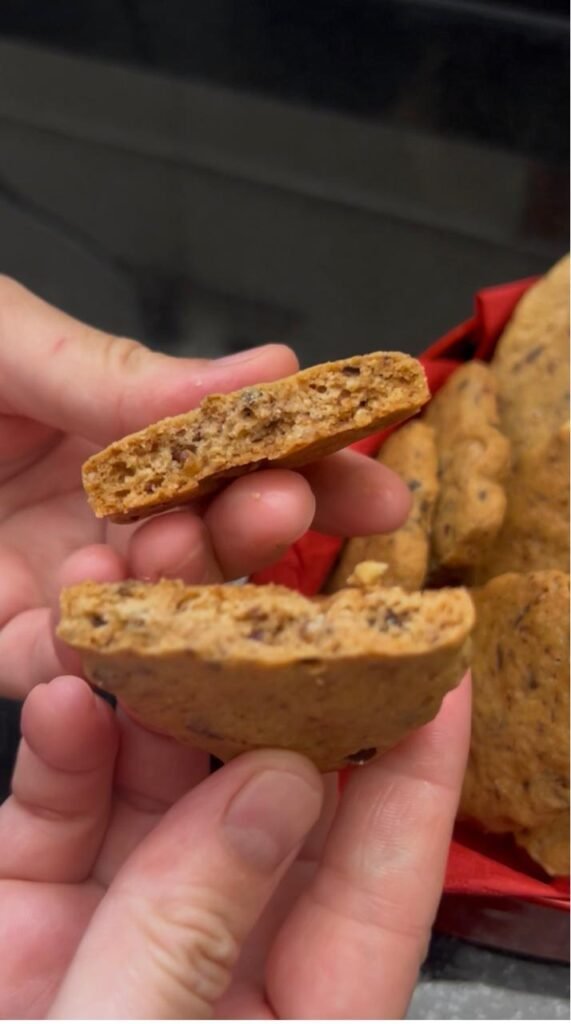 Close-up of chocolate walnut sablé cookie showing crispy, buttery texture and walnut pieces