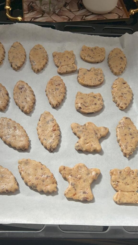 Cookie shapes cut with cutters from chocolate walnut sablé dough on parchment paper