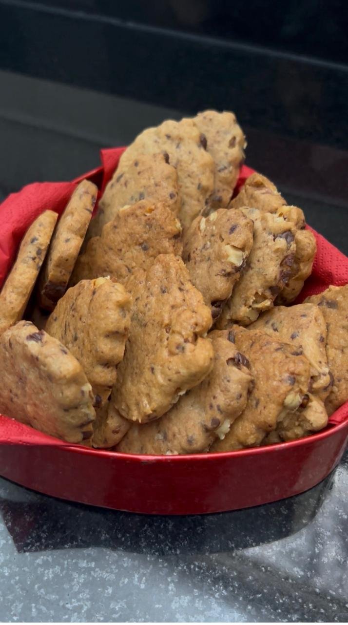 Chocolate walnut sablé cookies stacked on white plate showing delicate shapes and golden color
