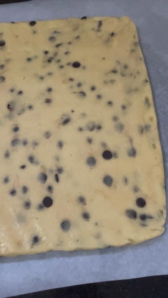 Cookie bar dough slab shaped on parchment paper ready for freezer, showing thickness and edges