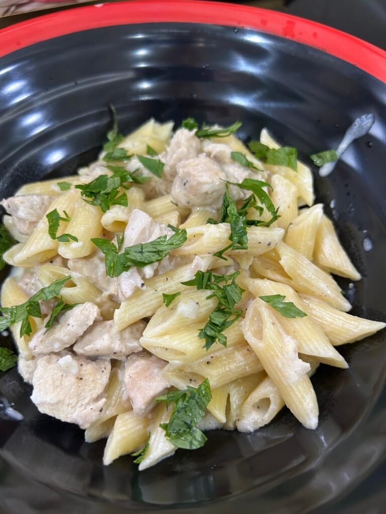 Easy creamy chicken penne finished and plated in black bowl with fresh parsley garnish