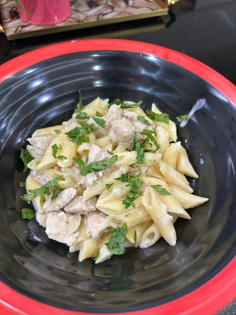 Easy creamy chicken penne finished and plated in black bowl with fresh parsley garnish
