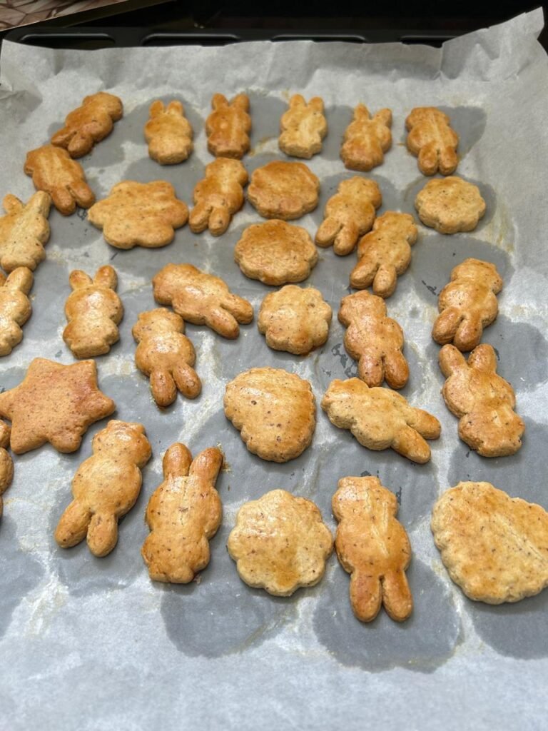 Golden almond sablé cookies fresh from oven showing golden-brown edges and matte golden glaze finish